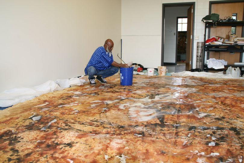 a picture of moyo okediji working on one of his art pieces in his art gallery