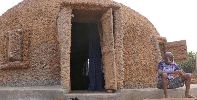 A PICTURE OF MOYO OKEDIJI OUTSIDE ONE OF THE SUITS OF THE AKOFI ORISA