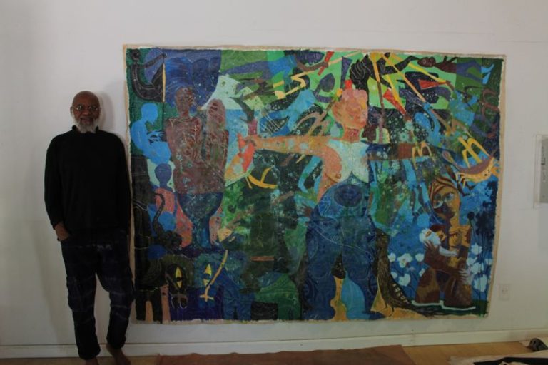 a picture showing moyo okediji standingnext to his artwork