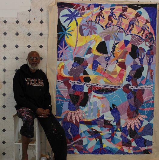 a picture showing moyo okediji sitting next to his artwork