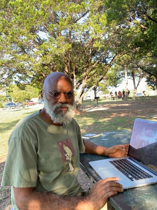 a picture showing moyo okediji working on his system under a tree poised for the camera