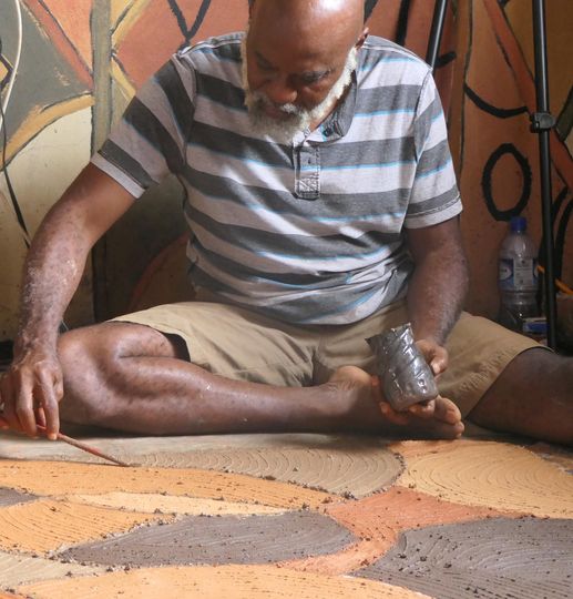 A picture of Moyo Okediji sitting in front of his artwork