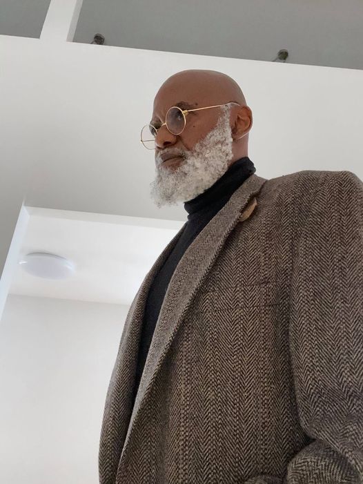 a picture showing moyo okediji poised for the camera in a greyish coloured coat and a black turtle neck.