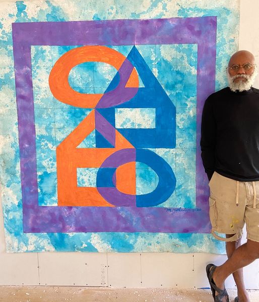 a picture showing moyo okediji standing next to his artwork