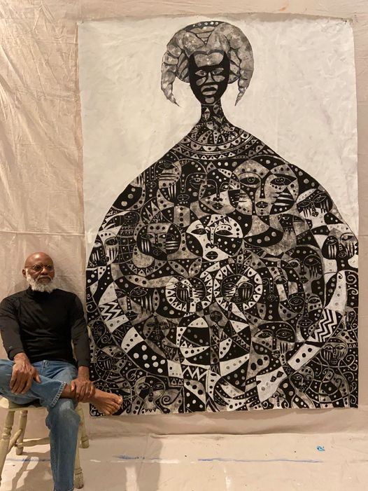 a picture showing moyo okediji sitting next to his artwork