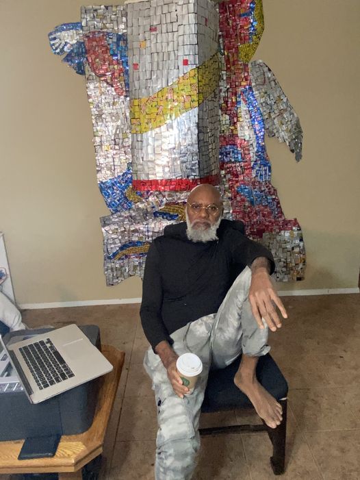 A picture of Moyo Okediji sitting in front of his artwork