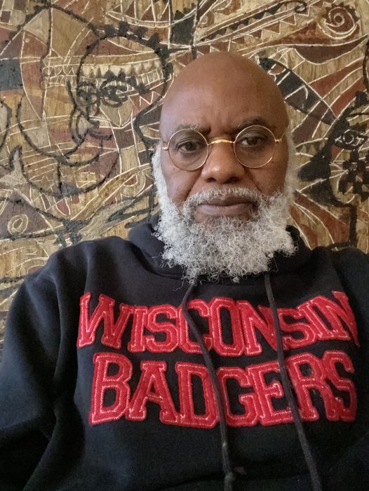 a picture showing moyo okediji sitting next to his artwork