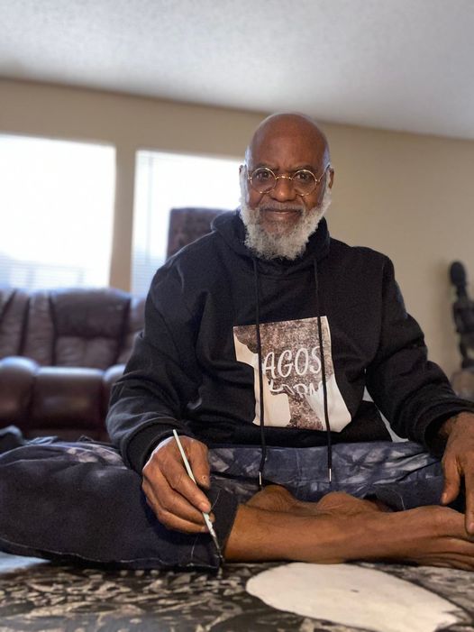 A picture of Moyo Okediji sitting in front of his artwork