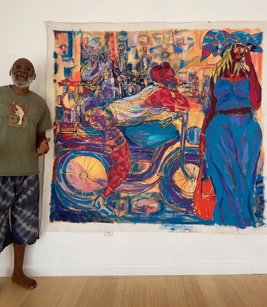 a picture showing moyo okediji standing next to his artwork