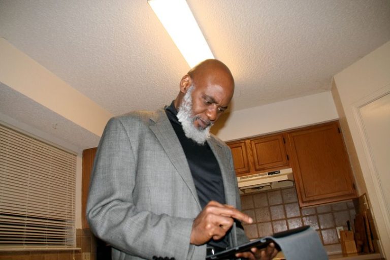 a picture showing moyo okediji poised for the camera in a greyish coloured coat and a black turtle neck.