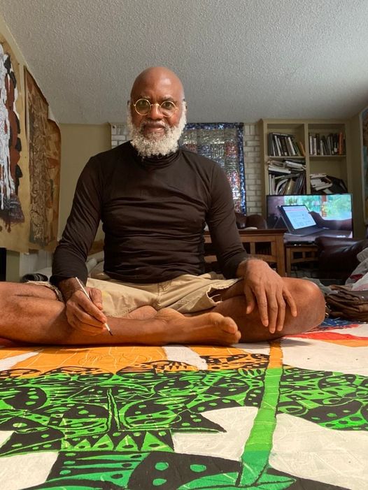 A picture of Moyo Okediji sitting in front of his artwork