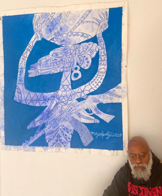 a picture showing moyo okediji sitting next to his artwork