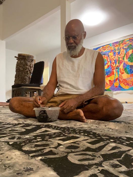 A picture of Moyo Okediji sitting in front of his artwork