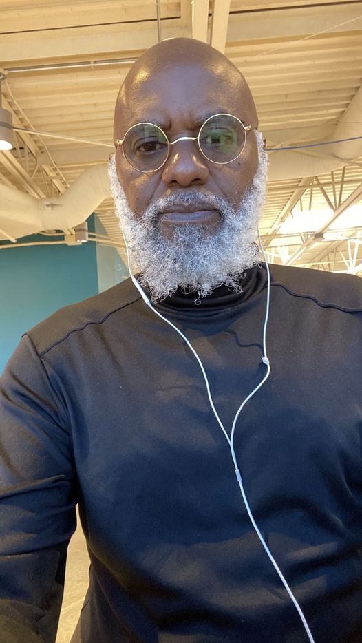 a picture showing moyo okediji sitting next to his artwork