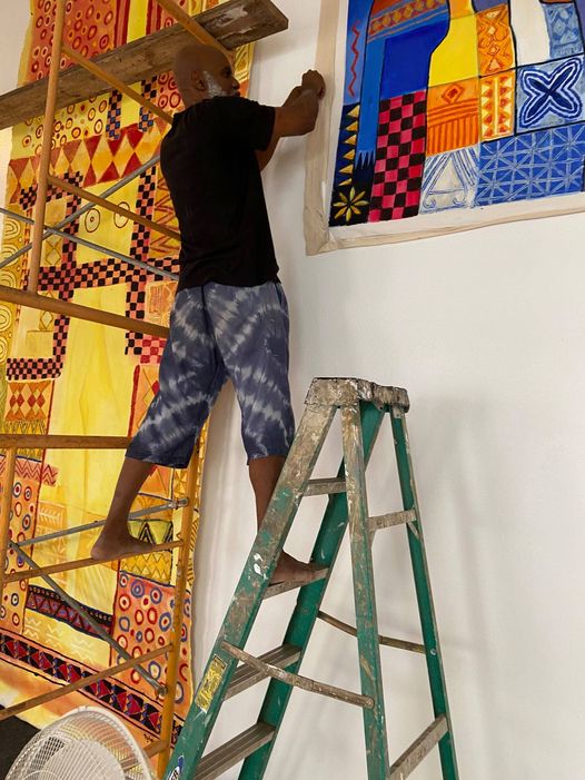 a picture of Moyo Okediji installing huge paintings by Adetola Wewe inside his gallery in Austin Texas.