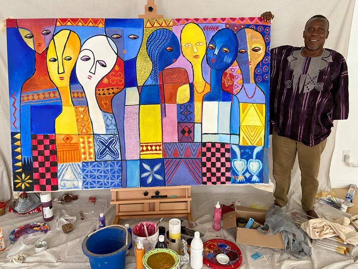 Adetola Wewe with moyo okediji in Austin, Texas, posing with the first painting he completed and signed as an artist in residence at the University of African Art Residency, Texas, Austin.